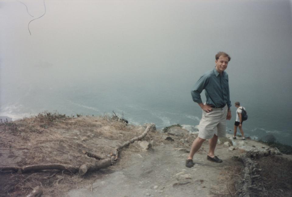 Elon Musk as a recent graduate from the University of Pennsylvania in the summer of 1995, showing him on a hiking trail high above a foggy San Francisco Bay