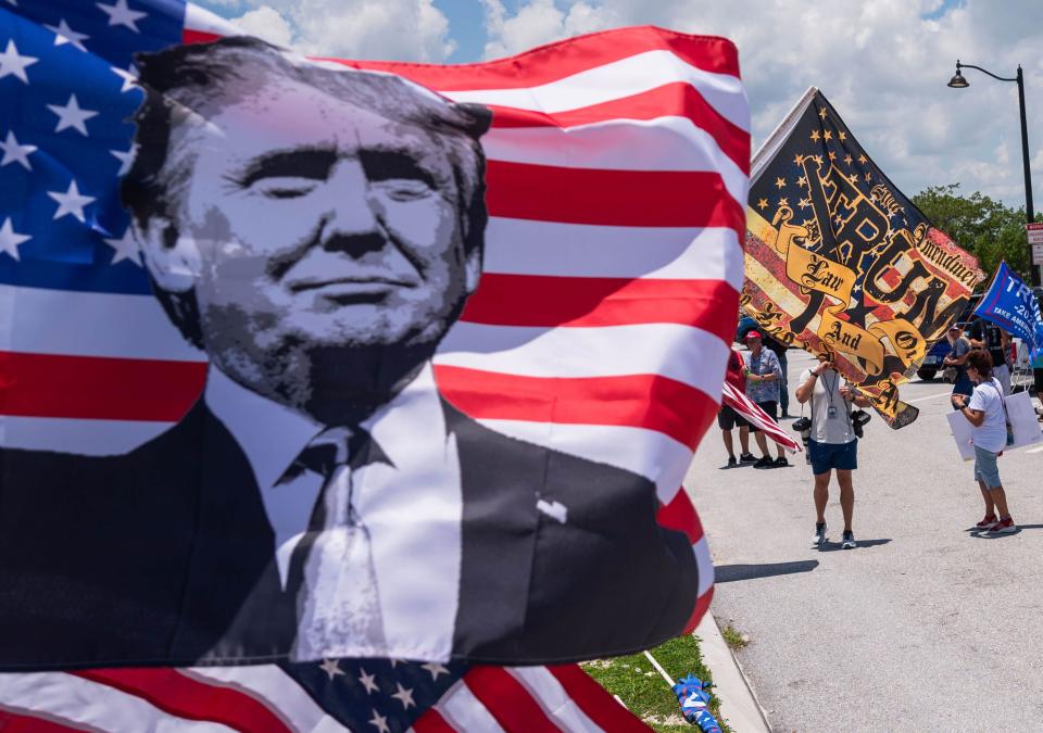 A group of supporters of the former President Donald Trump waves flags at passing traffic during a pro-Trump event on Sunday, June 11, 2023, on the bridge portion of Southern Boulevard in West Palm Beach, Fla.