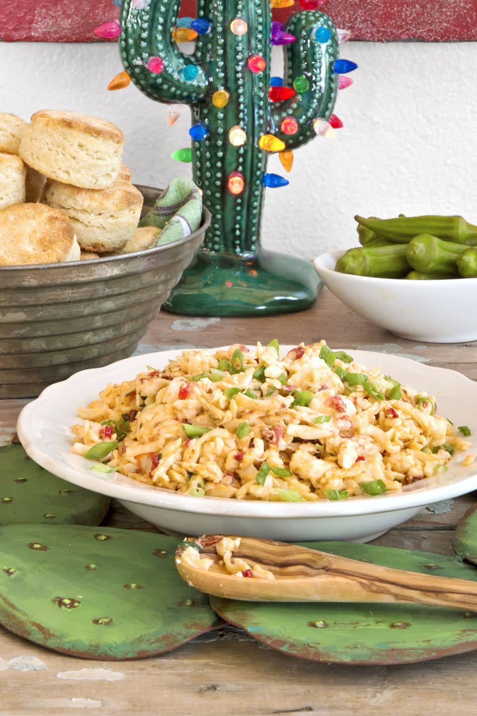 texas style pimento cheese in a shallow white bowl with a wooden spoon for serving