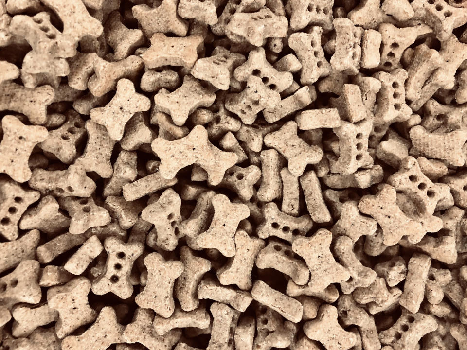 A pile of dog treats shaped like bones and paws, closely stacked together