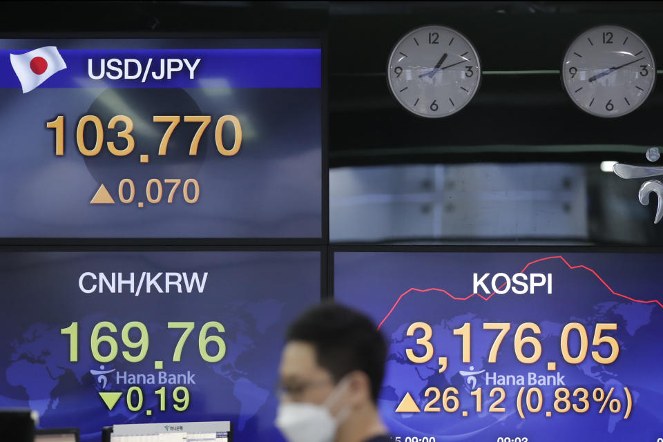 A currency trader walks by the screens showing the Korea Composite Stock Price Index (KOSPI), right, and the foreign exchange rates at the foreign exchange dealing room in Seoul, South Korea, Friday, Jan. 15, 2021. Asian shares were mixed on Friday after a late slide in several Big Tech stocks left major indexes lower on Wall Street. (AP Photo/Lee Jin-man)