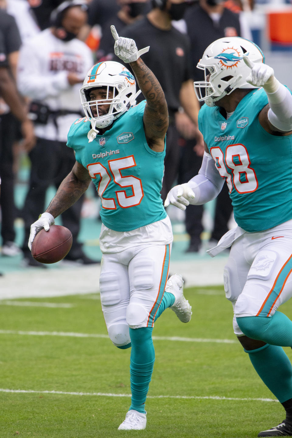 FILE - Miami Dolphins cornerback Xavien Howard (25) points to the sky as he celebrates intercepting a pass intended for Cincinnati Bengals wide receiver Tyler Boyd (not shown) along with Miami Dolphins defensive tackle Raekwon Davis (98) during an NFL football game in Miami Gardens, Fla., in this Sunday, Dec. 6, 2020, file photo. All-Pro cornerback and reigning NFL interception leader Xavien Howard wants a new contract from the Miami Dolphins, and there is no guarantee he will attend the three-day mandatory minicamp starting Tuesday, June 15, 2021. (AP Photo/Doug Murray, File)