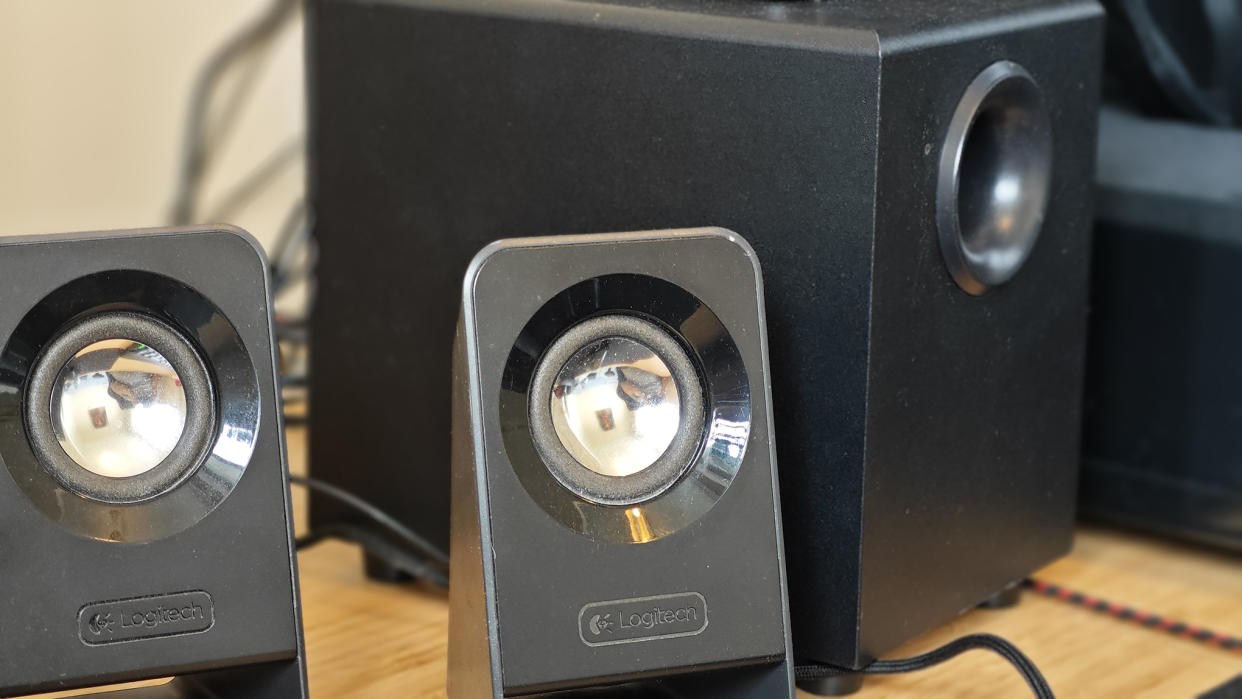  Black Logitech Z213 speakers sitting on a wooden desk 