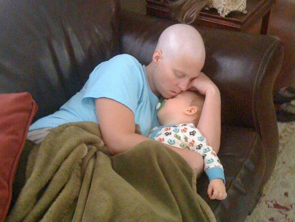 Cancer patient Elizabeth O'Connor cuddles her toddler son on a leather couch.