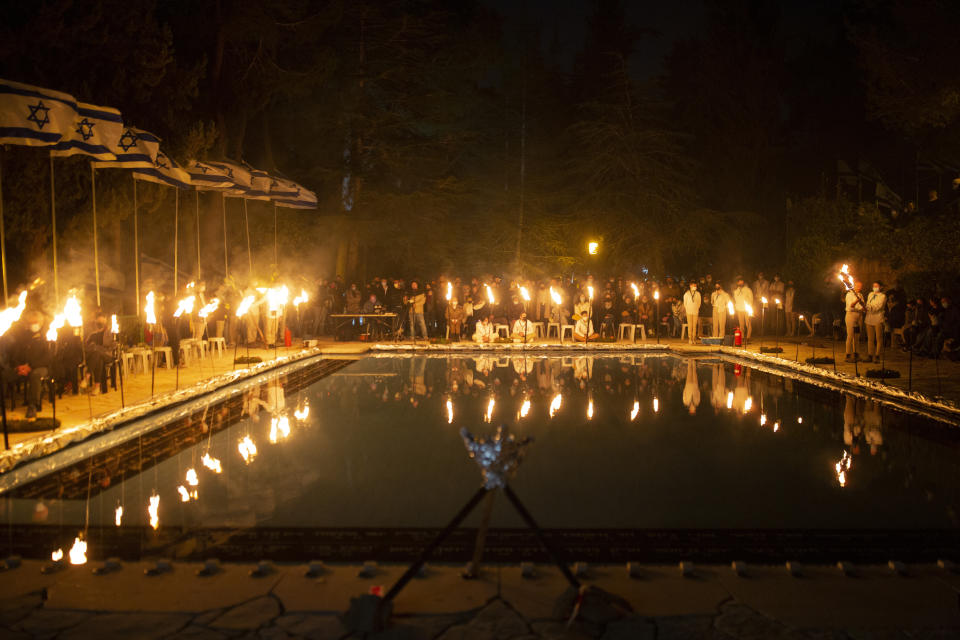 Israeli scouts light torches during a Memorial Day ceremony commemorating fallen soldiers, at the military cemetery at Mount Herzl in Jerusalem, Tuesday, April 13, 2021. (AP Photo/Maya Alleruzzo)