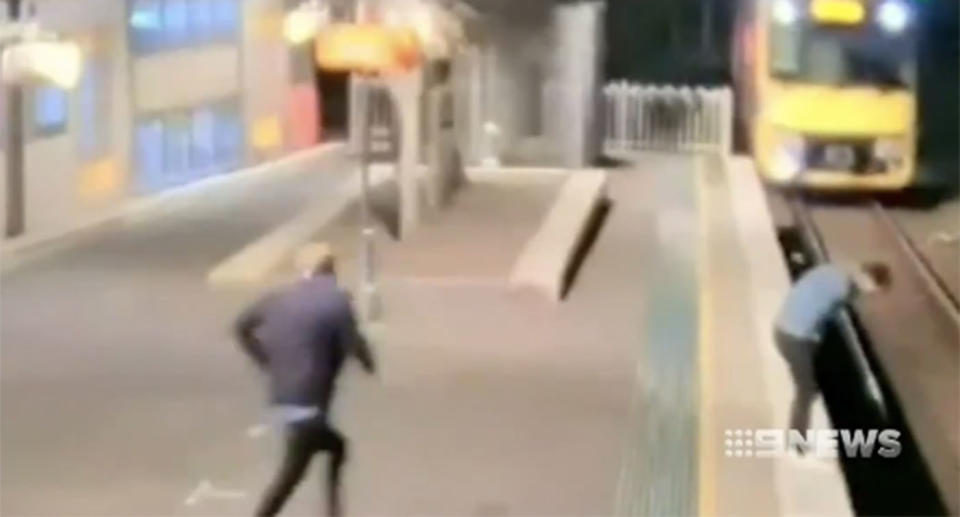 A man runs toward a commuter feeling unwell on the edge of the platform as a train approaches on a Sydney train station. Source: 9 News