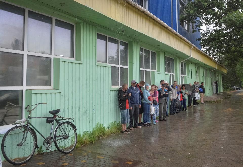 Local residents wait in a line during rain, near a humanitarian aid centre (REUTERS)