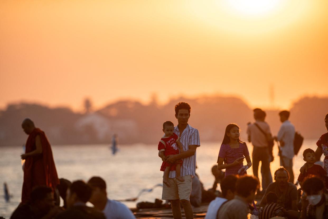 People gather to observe the last sunset of the year at the Botahtaung jetty on Yangon River in Yangon (AFP via Getty Images)