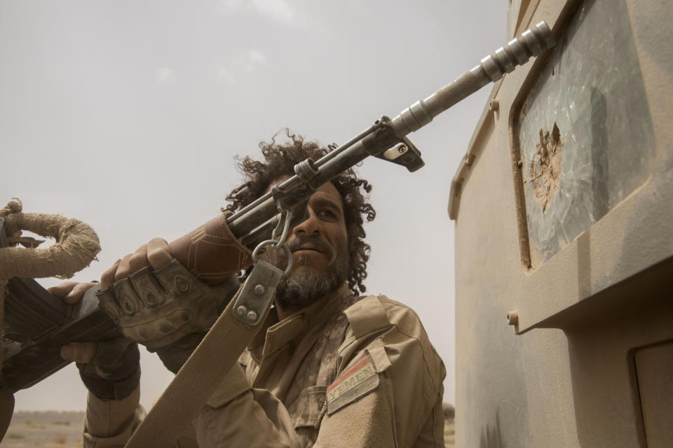 A Yemeni fighter backed by the Saudi-led coalition looks at damage to the back of an armored vehicle as they leave the front lines near Marib, Yemen, Saturday, June 19, 2021. (AP Photo/Nariman El-Mofty)