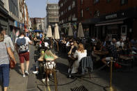 People sit outside on a street closed to traffic to try to reduce the spread of coronavirus so bars, cafes and restaurants can continue to stay open, in the Soho area of central London, Saturday, Sept. 19, 2020. Fresh nationwide lockdown restrictions in England appear to be on the cards soon as the British government targeted more areas Friday in an attempt to suppress a sharp spike in new coronavirus infections. (AP Photo/Matt Dunham)