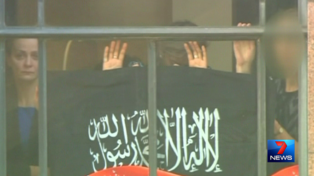 Hostages were forced to hold a flag against the Lindt Cafe window. Source: 7News