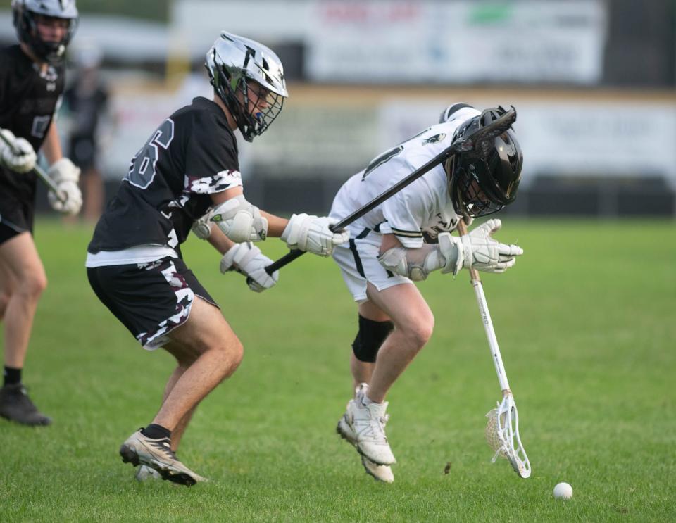 Elijah Busby (26) and Colin Goodman (31) fight for the ball during the Navarre vs Milton boys lacrosse game at Milton High School on Monday, March 27, 2023.