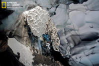 A mix of ropes and ladders eases access to Warren Cave, a labyrinth of passages melted from the ice by the volcano's heat. Small currents of air probably cause the scalloping around the cave's entrance. (photo © Carsten Peter/National Geographic)