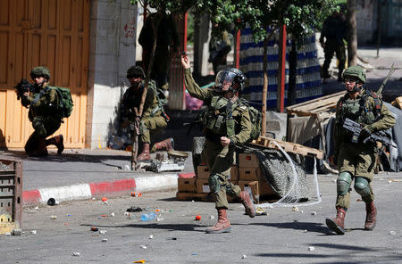An Israeli soldier hurls a sound grenade towards Palestinians during clashes in Hebron in the occupied West Bank, June 29, 2018. REUTERS/Mussa Qawasma