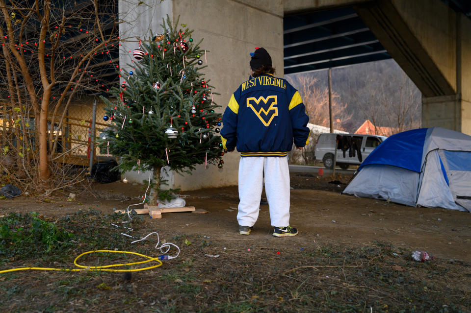 Chrissy stands by a Christmas tree in her encampment on Dec. 9. Chrissy helped bring the tree with others to hold a celebration and sing carols. After complaints, the City of Wheeling removed the tree's power, citing that they agreed to supply electricity for a temporary shower station adjacent to the camp but had not agreed to have it used for anything else.<span class="copyright">Rebecca Kiger</span>