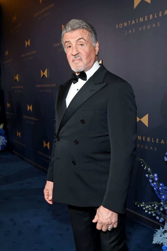 Sylvester Stallone in black suit and bow tie on event background