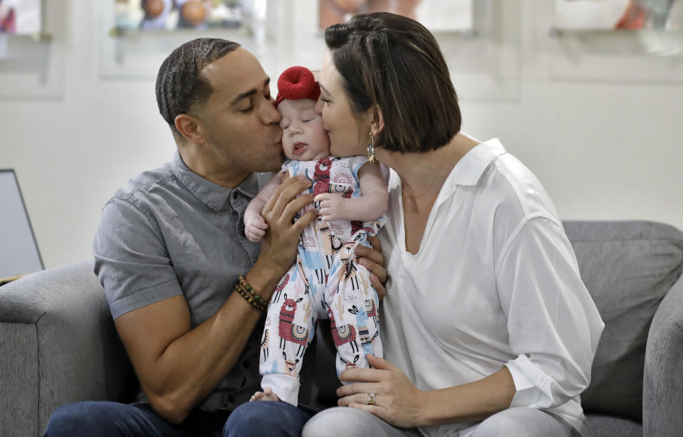 NBA referees Jonathan Sterling, left, and Lauren Holtkamp-Sterling, the only married couple in NBA refereeing history, pose for a photo with their daughter Stoan at their home Thursday, Oct. 3, 2019, in Tampa, Fla. (AP Photo/Chris O'Meara)