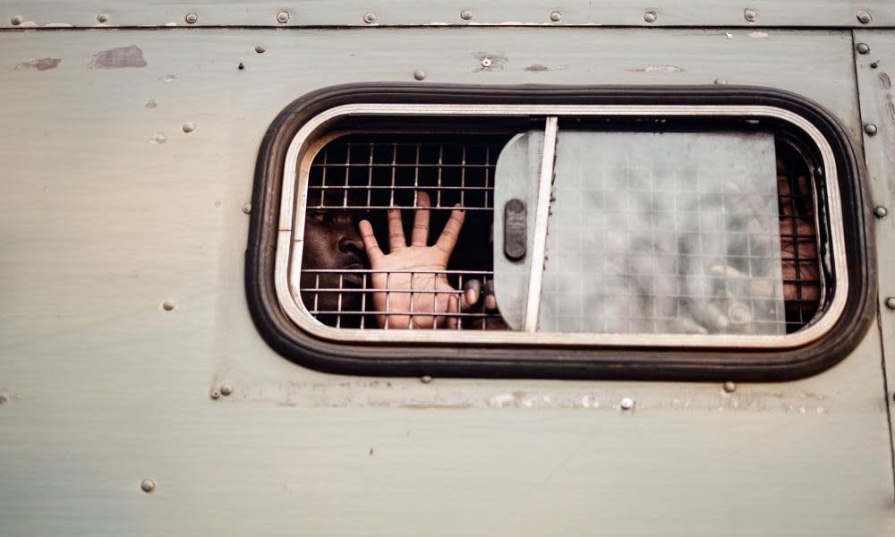 An MDC supporter gestures the party’s symbol from a prison truck outside Harare magistrates court