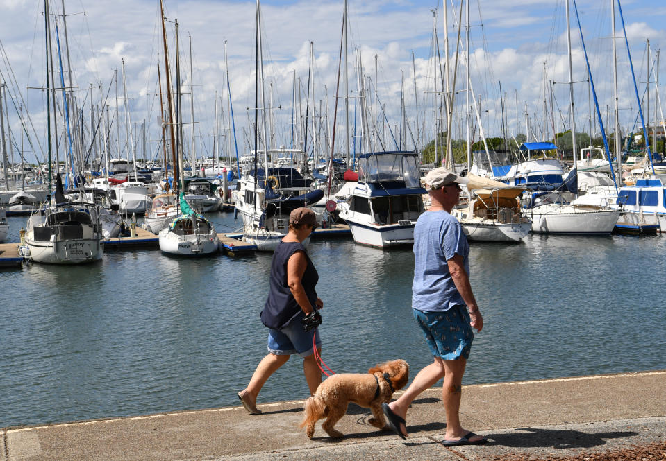 People are seen walking their dog past Manly Boat Harbour in Brisbane, Wednesday, April 1, 2020. Source: AAP