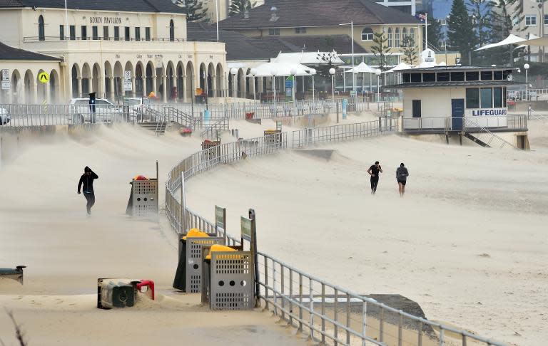 Joggers struggle against sand whipped up by strong winds, at Bondi Beach in Sydney, on April 21, 2015