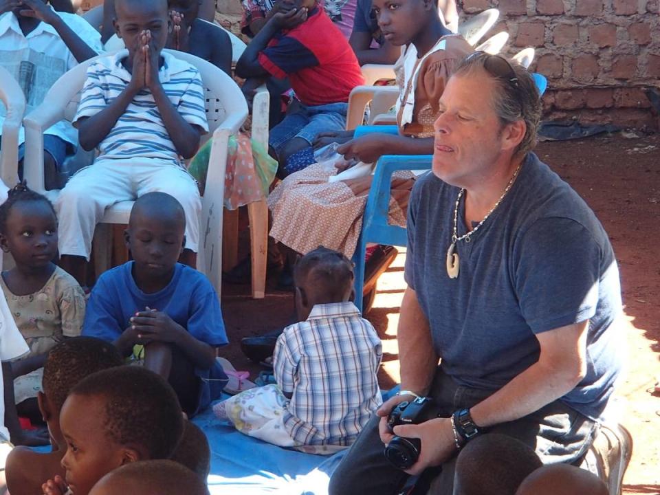 Mike Forster is seen here with several children in a village in Uganda, where he went on several annual missions to help poor children.