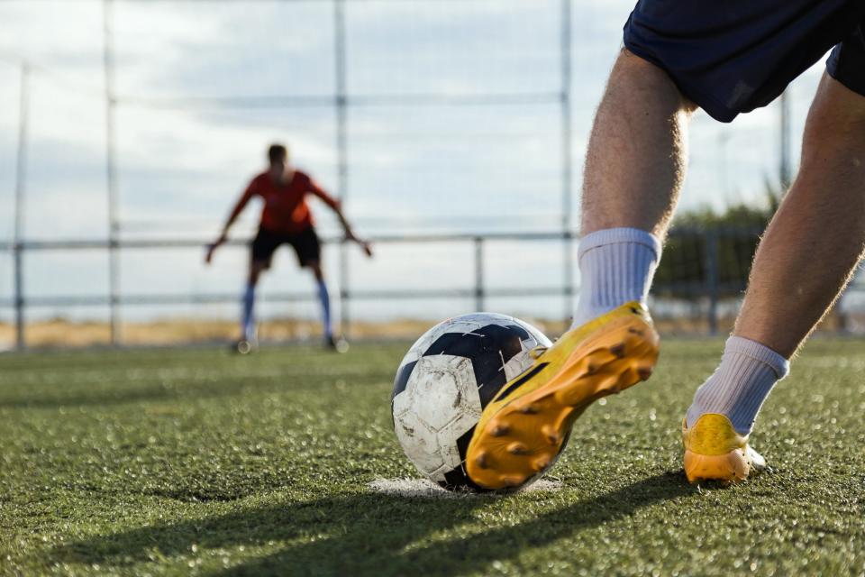 Soccer player kicks a ball. Horizontal outdoors shot