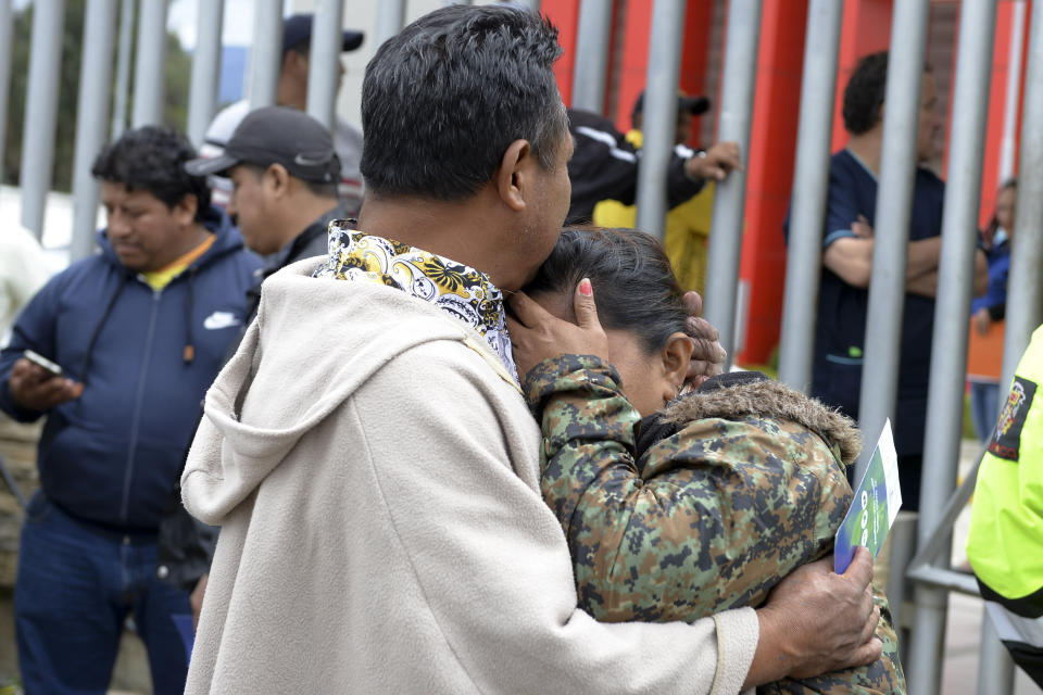 La gente se abraza mientras espera noticias afuera de la morgue sobre sus familiares, quienes eran hinchas de un equipo de futbol y fallecieron en un accidente de autobús en Cuenca, Ecuador, el lunes 13 de agosto de 2018. (AP Foto/Javier Ramirez)