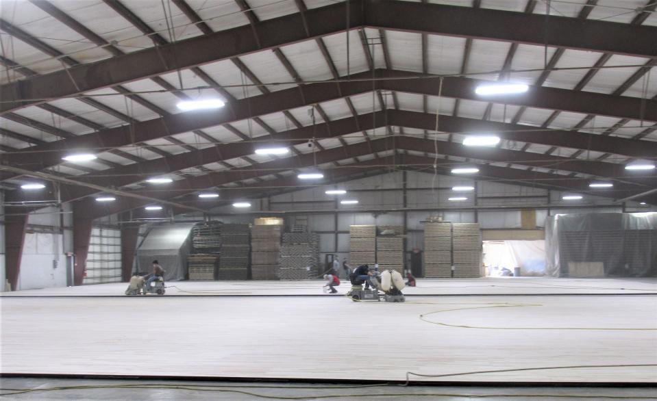 Ohio Floor Company staff work on finishing basketball courts inside their warehouse in the Holmesville Industrial Park on County Road 242.