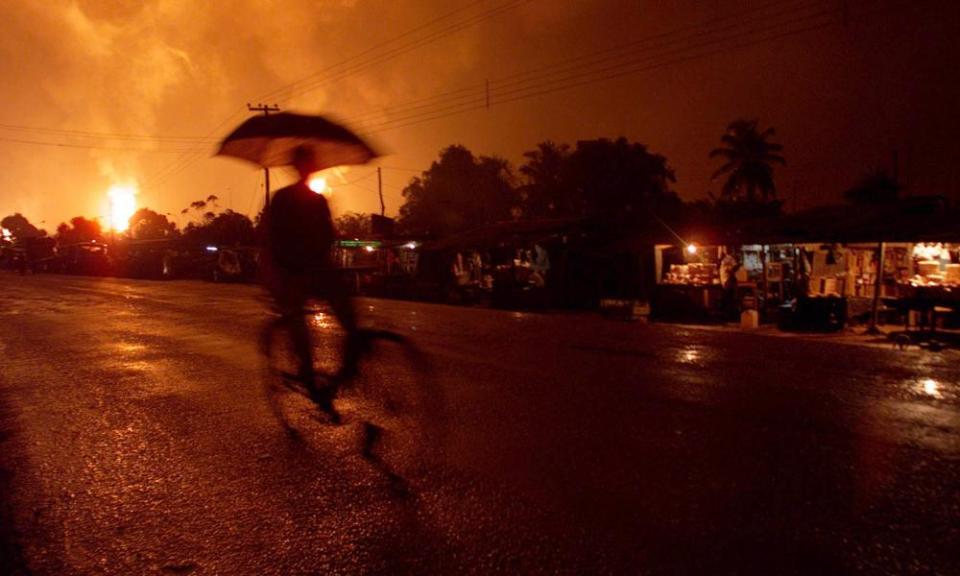 A villager bicycles on the main road lit by burning natural gas flares in Ebocha, Nigeria.