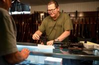 Gun shop owner Shane Wyatt shows a customer a 9 mm handgun, in Norton, Kansas