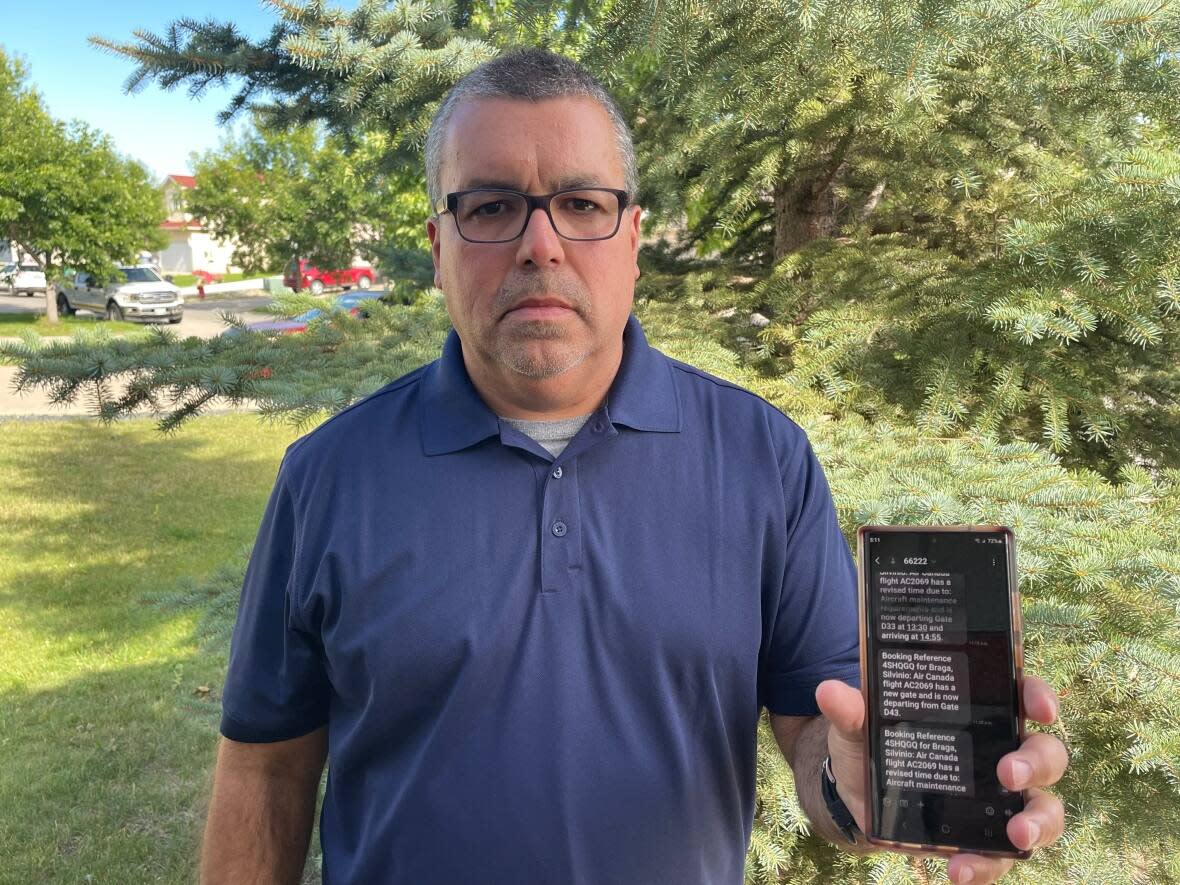 Silvino Braga said he's very disappointed and even pained by his experience with Air Canada. He holds up his phone, which shows many messages from Air Canada changing his flight details. (Submitted by Cristina Braga - image credit)