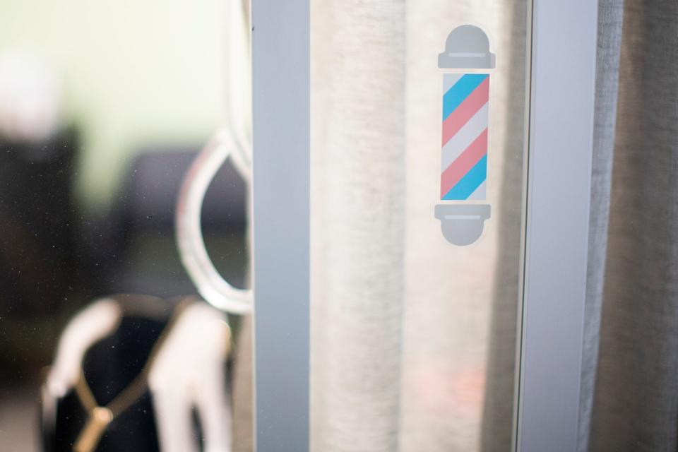 A barbershop pole sticker, featuring the colors of the trans flag, is pictured on the window of Hair by Sarah Turville, a salon that participates in the Strands for Trans network.