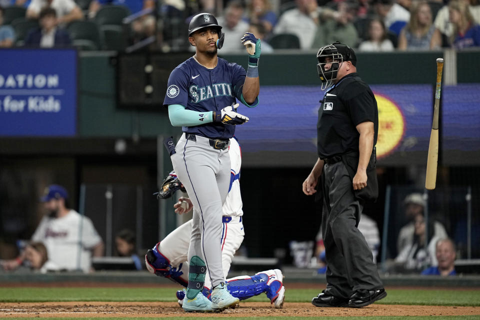 Seattle Mariners' Julio Rodriguez tosses his bat and prepares to head to first after earning a walk during the fifth inning of a baseball game Tuesday, April 23, 2024, in Arlington, Texas. (AP Photo/Tony Gutierrez)