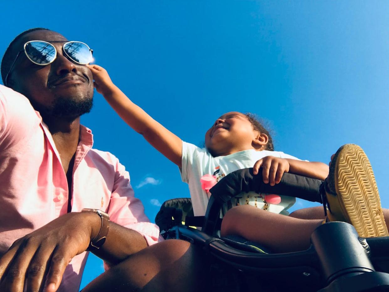 11 ideas for road trip activities for kids. Pictured: a girl in a stroller grabbing her dad's sunglasses.