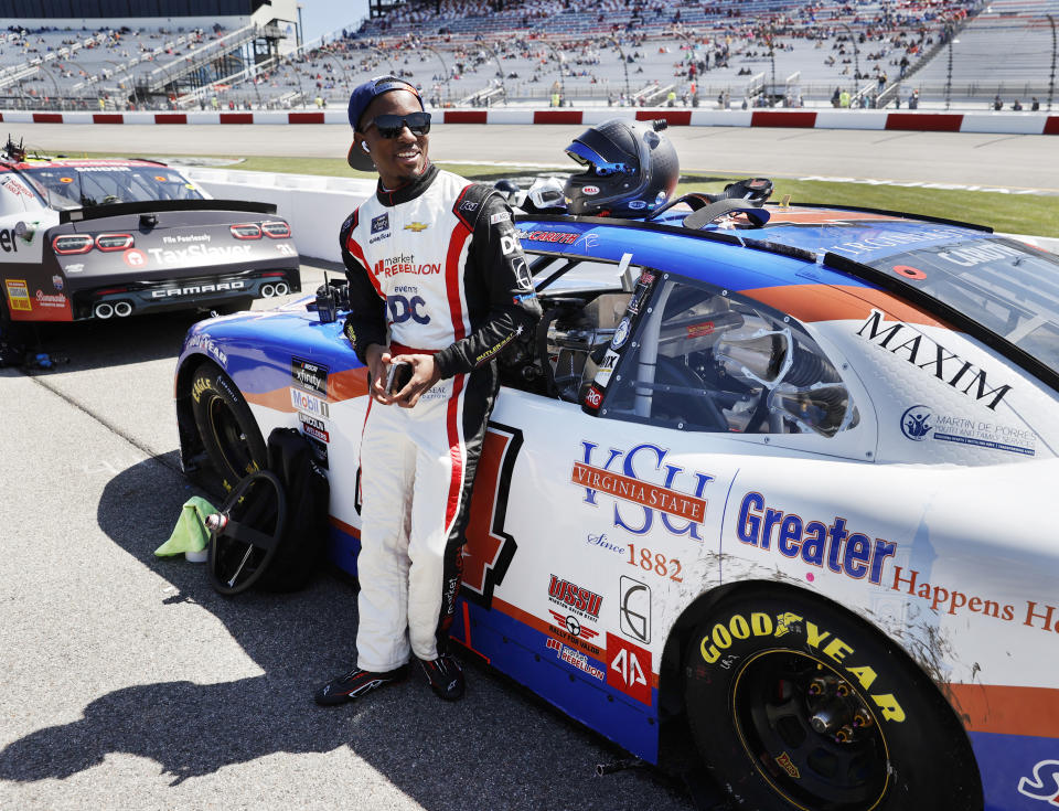 FILE -Rajah Caruth stands by his Virginia State University Chevrolet prior to a NASCAR Xfinity Series auto race at Richmond Raceway, Saturday, April 2, 2022, in Richmond, Va. With NASCAR celebrating its 75th anniversary in 2023, The Associated Press asked Rajah Caruth, a 20-year-old graduate of the “Drive for Diversity” program and a student at Winston-Salem State, to write an essay on the series and its role in his life: (James H. Wallace/Richmond Times-Dispatch via AP)