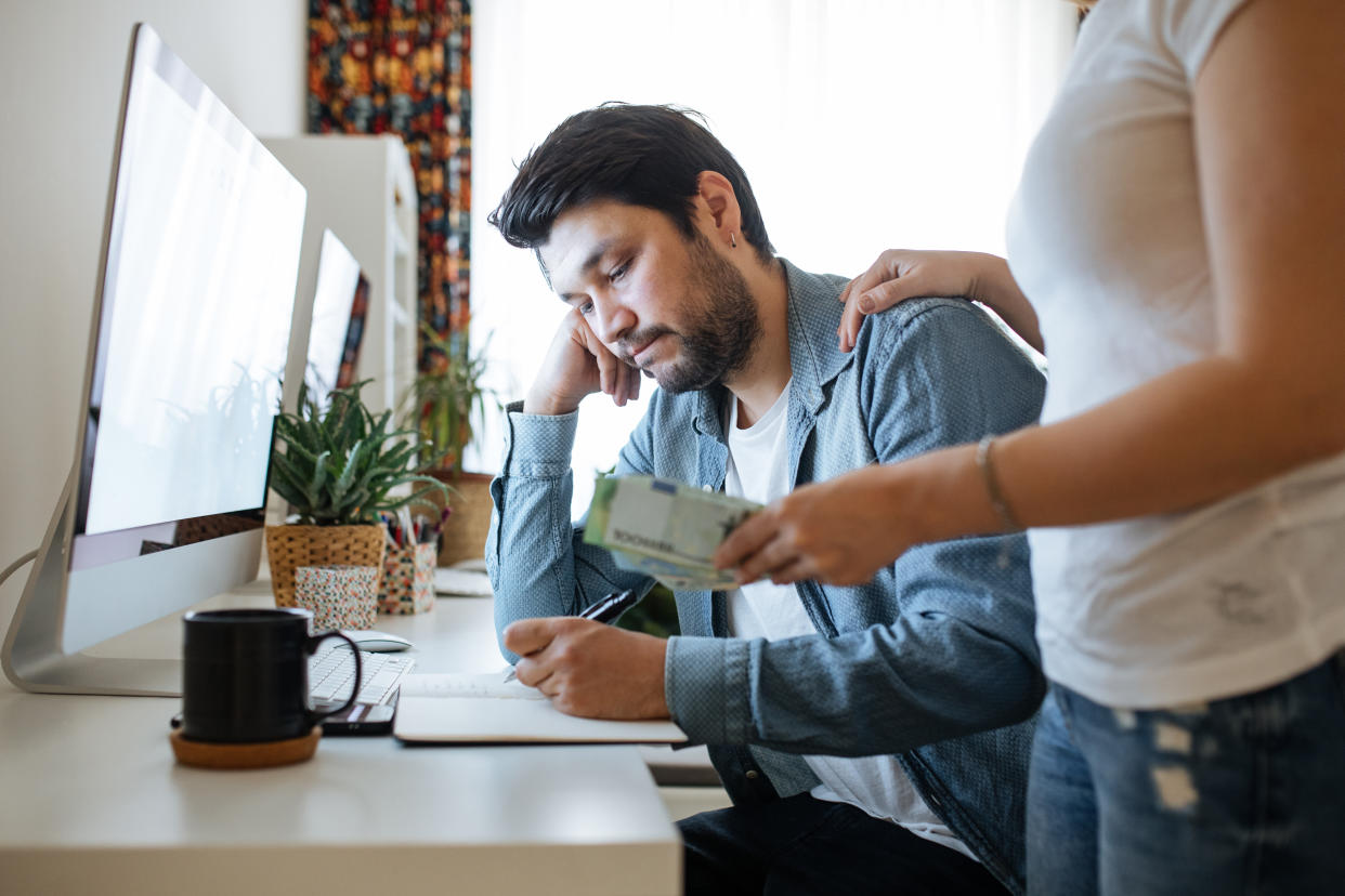 Serious young couple checking documents with using computer