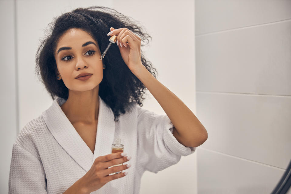 Portrait of a gorgeous woman applying a facial serum to her skin before the mirror