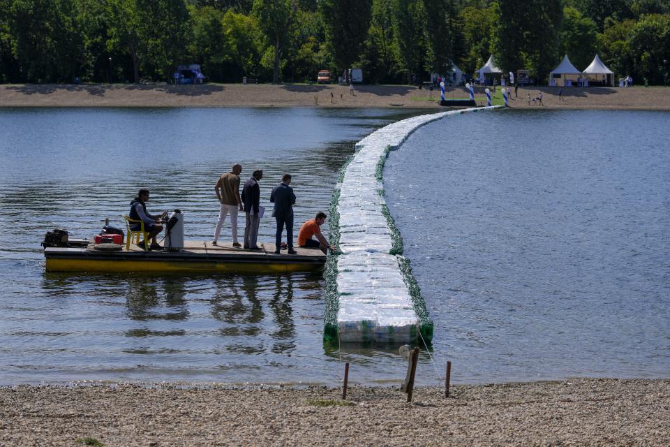 FILE - People inspect a floating bridge made from plastic bottles positioned in the Ada Ciganlija Lake in Belgrade, Serbia, July 27, 2023. (AP Photo/Darko Vojinovic, File)
