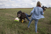 A Syrian refugee, Osama Abdul Mohsen, carrying his youngest son Zaid falls after being tripped by TV camerawoman Petra Laszlo (R) while trying to escape from a collection point in Roszke village, Hungary, September 8, 2015. REUTERS/Marko Djurica/File Photo