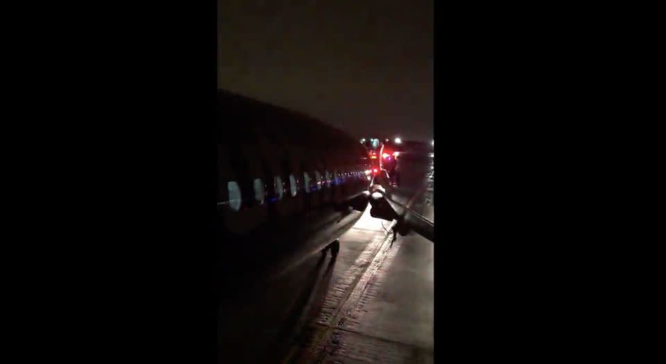 Passengers jump onto the escape slide. Source: Twitter/Brandon Coxsize=O