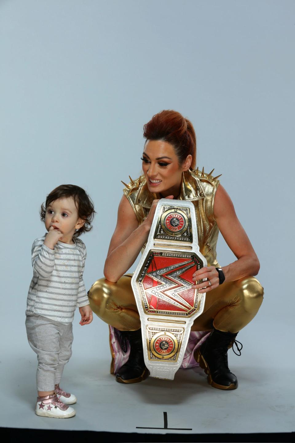 Becky Lynch, WWE belt in hand, poses with daughter Roux.