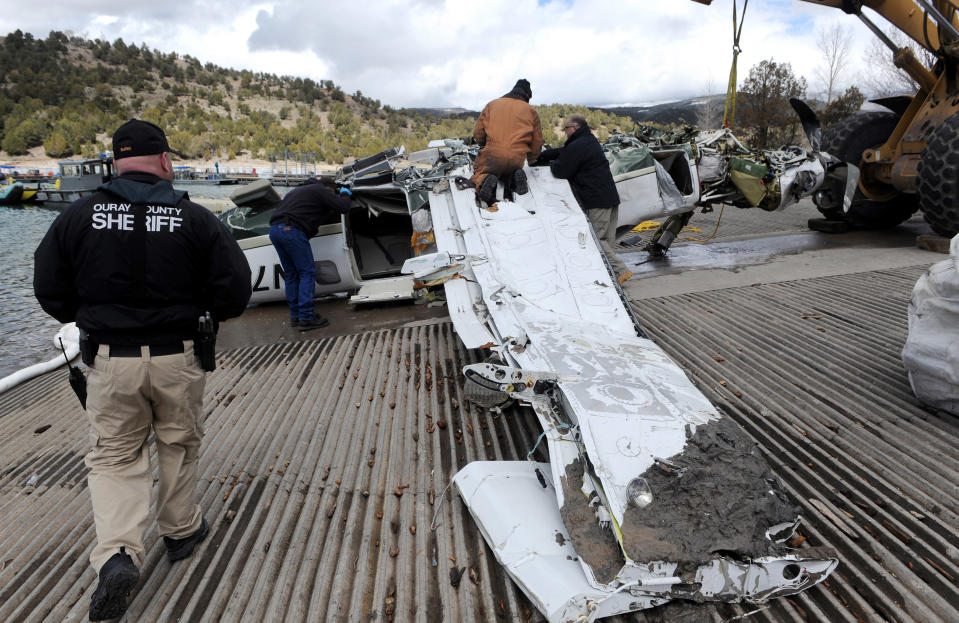 This photo released by Ouray County shows officials examining the aircraft after it was recovered with the five victims on Thursday March 27, 2014, at the Ridgway Reservoir near Ridgway, Colo., The plane crashed last Saturday, March 22, 2014, killing five people from Alabama. (AP Photo/Ouray County, William Woody)