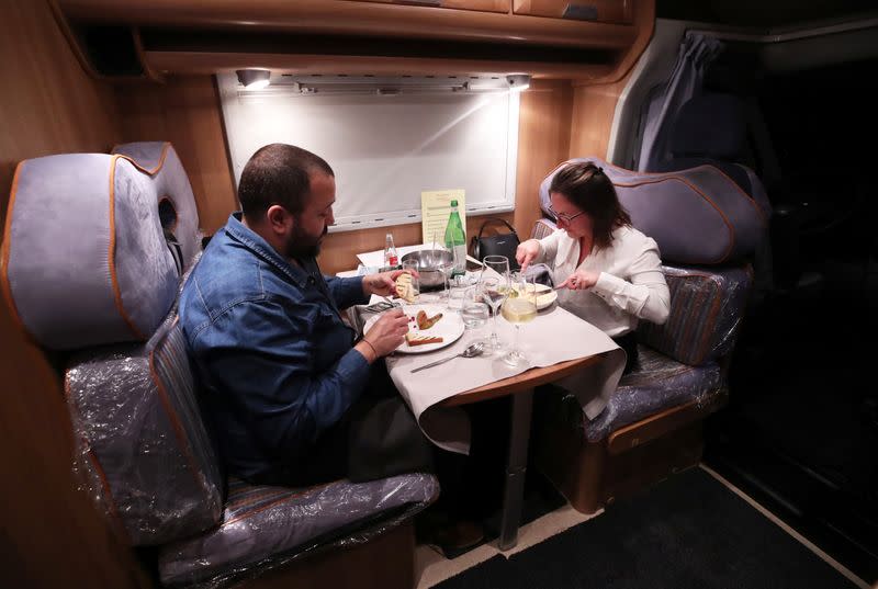 Customers enjoy a dinner sitting inside a motorhome (camping car) parked on the parking of the Belgian restaurant Matthias And Sea despite the lockdown amid the coronavirus disease (COVID-19) pandemic in Tarcienne