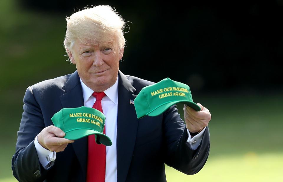 President Donald Trump holds up two hats that say "Make Our Farmers Great Again" as he departs the White House August 30, 2018 in Washington, DC. Trump is scheduled to attend events in Indiana later today. (Photo: Win McNamee/Getty Images)