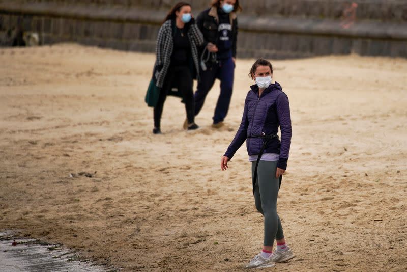 Beachgoers wear face masks at St Kilda beach in Melbourne, the first city in Australia to enforce mask-wearing to curb a resurgence of COVID-19