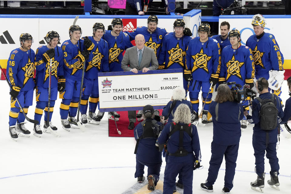 Joe Daly, center, presents NHL All-Star Team Matthews with their victory check after winning hockey's NHL All-Star Game in Toronto, Saturday, Feb. 3, 2024. (Nathan Denette/The Canadian Press via AP)