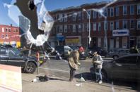 Two women sweeping up the streets are reflected in the broken window of a store in Baltimore, Maryland, April 28, 2015