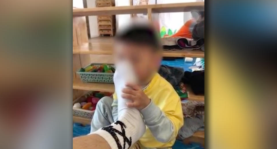 Image of boy sniffing what appears to be a man's foot.