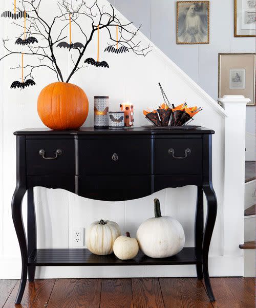 <p>Use a pumpkin to dangle some teeny, tiny bats. First, cut the stem flat across the top of the pumpkin. Carve out a small hole in the top that will hold several branches to create a treetop. Use patterned Halloween papers to cut out bat shapes. Tape a <a href="https://www.amazon.com/Topenca-Supplies-Inches-Double-Ribbon/dp/B01ENR4KE2/?tag=syn-yahoo-20&ascsubtag=%5Bartid%7C10055.g.1566%5Bsrc%7Cyahoo-us" rel="nofollow noopener" target="_blank" data-ylk="slk:thin ribbon;elm:context_link;itc:0;sec:content-canvas" class="link ">thin ribbon</a> from the back of each bat and tie to secure to branches. </p>