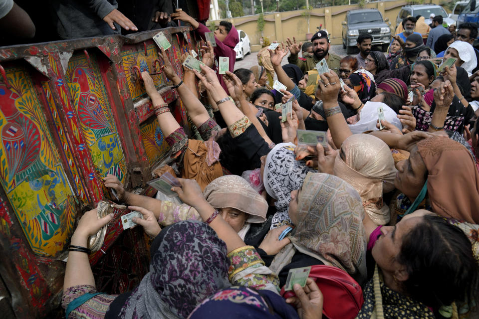 Women show their identity cards to receive a free sack of wheat flour at a distributing point, in Lahore, Pakistan, Monday, March 20, 2023. Pakistan's Prime Minister Shahbaz Sharif will provide free flour to deserving and poor families during the Muslim's holy month of Ramadan due to high inflation in the country. (AP Photo/K.M. Chaudary)